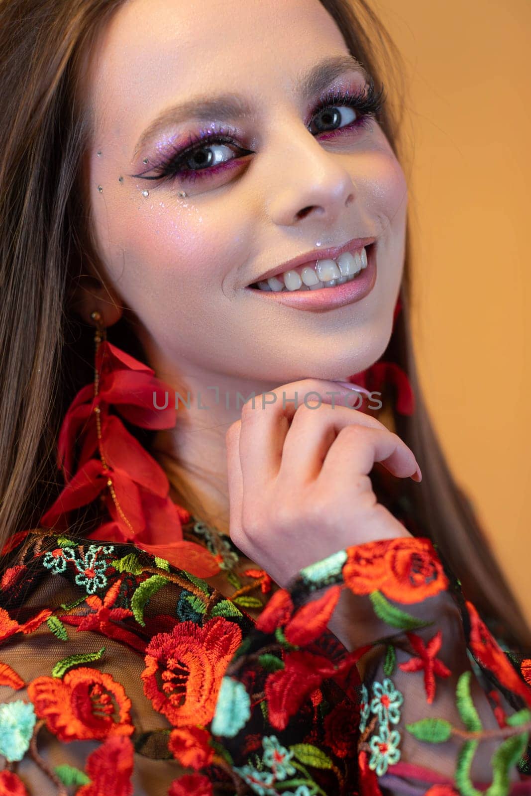 A smiling young woman proudly showcases her colorful makeup along with her stylish floral attire ensemble