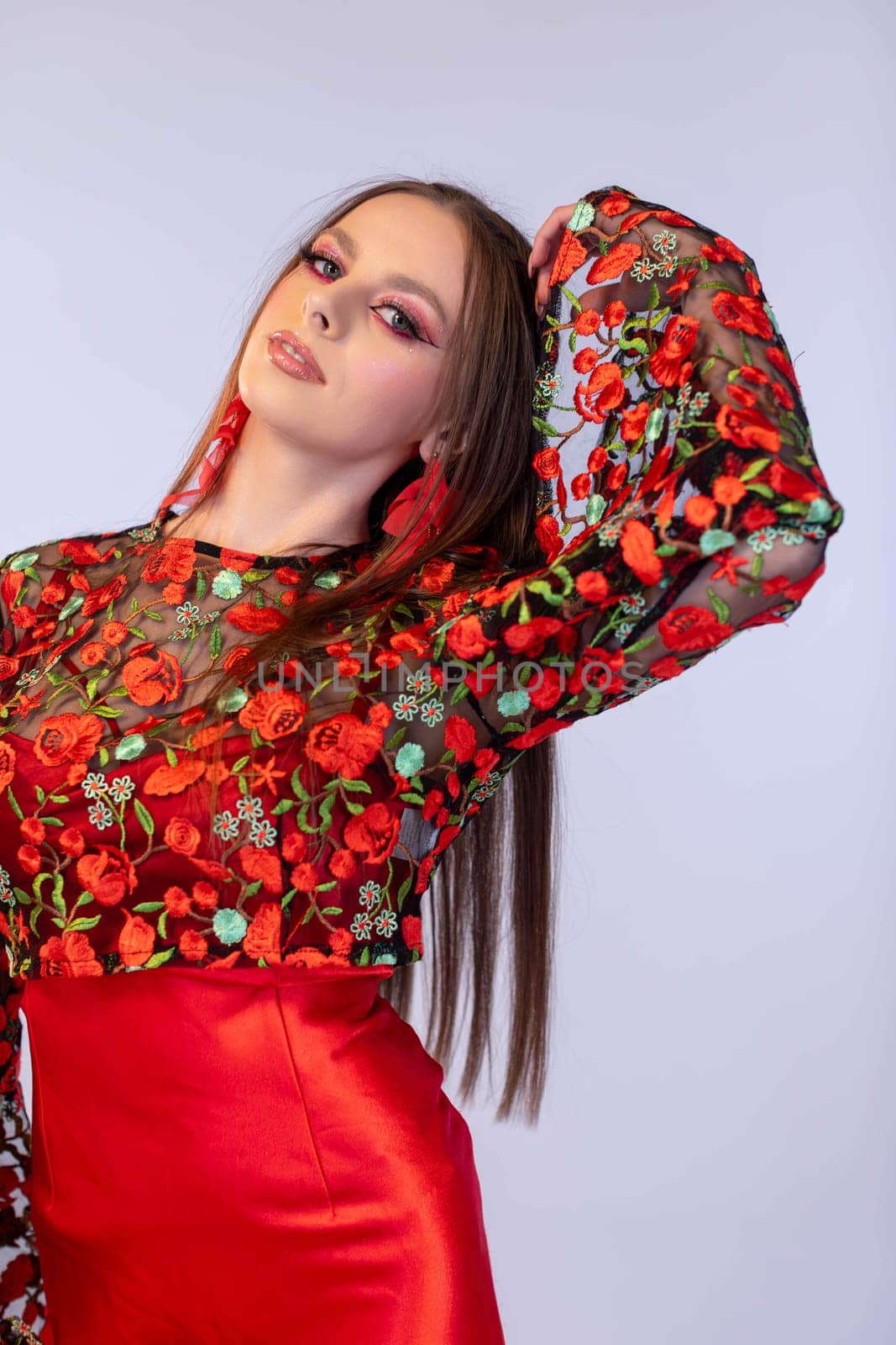 A fashion model poses elegantly in a vibrant red floral outfit, showcasing a beautiful blend of style and elegance