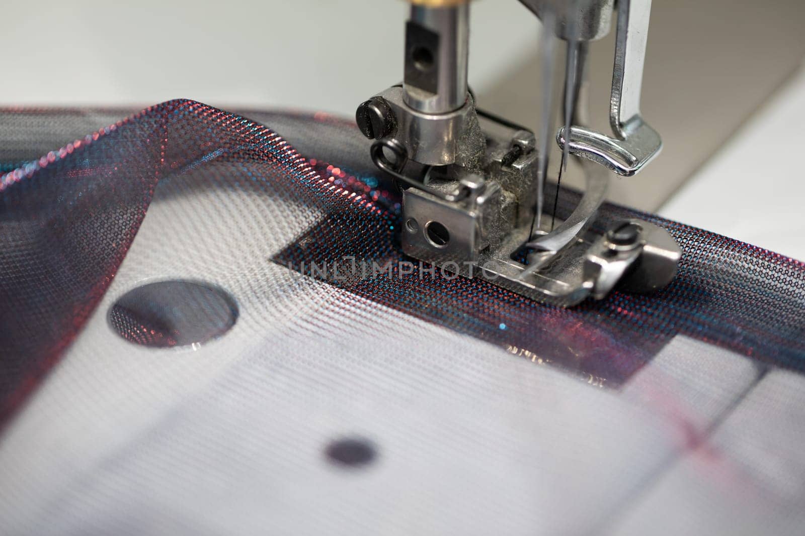 A detailed view of a sewing machine skillfully working on delicate fabric while using colorful threads artistically