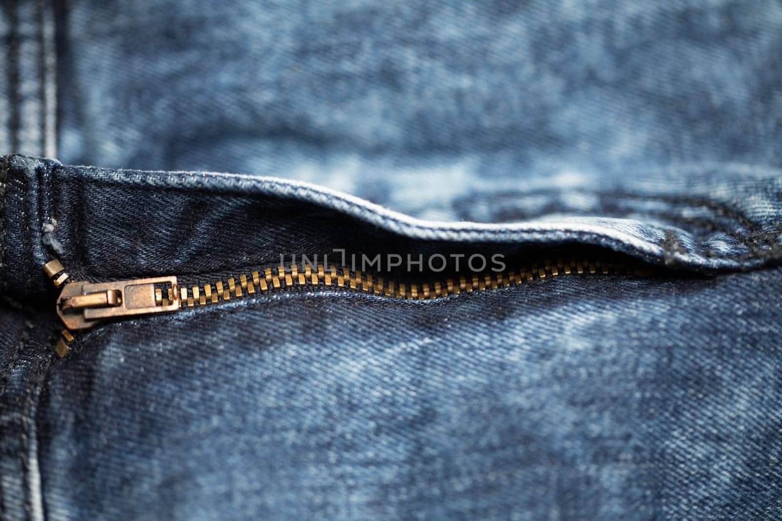 A detailed view of a zipper on a pair of blue denim jeans, showcasing classic style and craftsmanship.