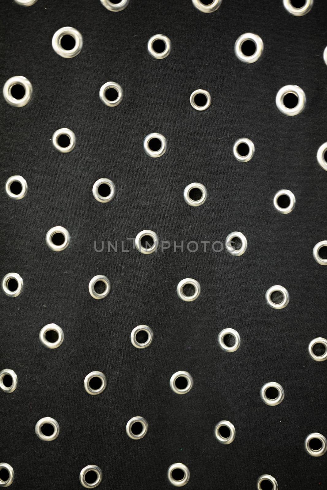 This black fabric with circular eyelets is perfect for fashion design and creative projects, making it versatile