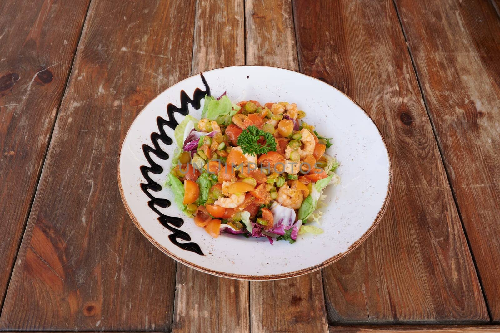 A plate of food with a white plate and a brown rim. The plate has a design on it and is topped with a sauce