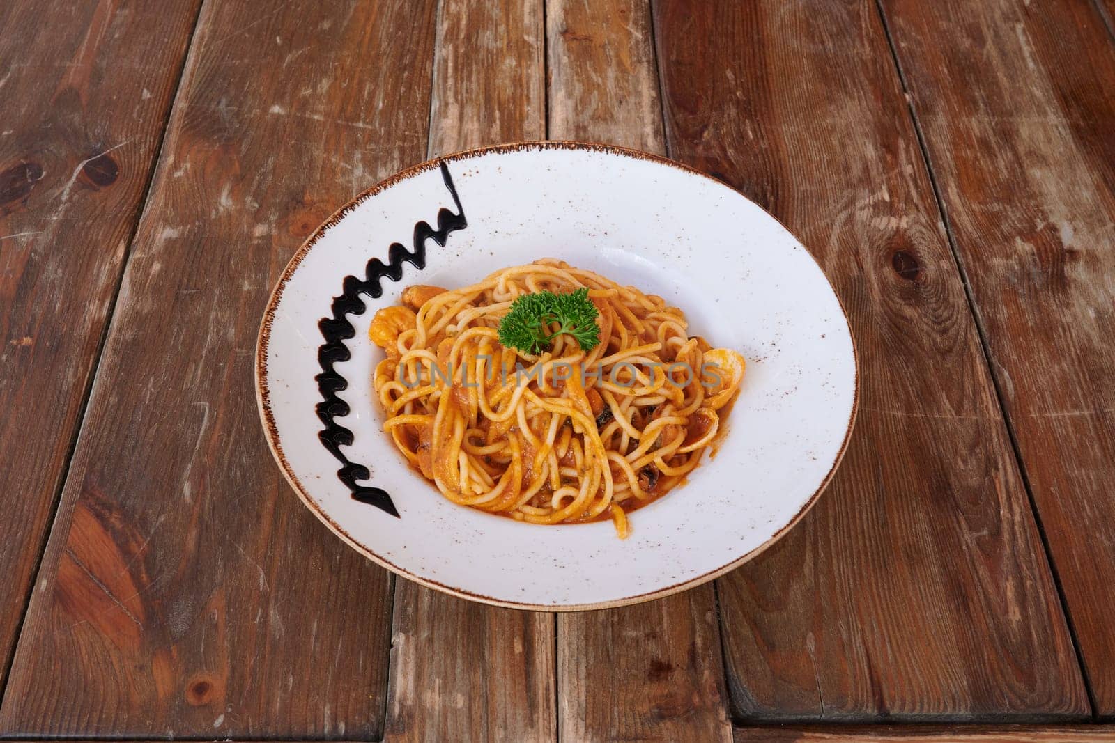 A plate of spaghetti with a black marker on it. The spaghetti is covered in sauce and topped with parsley