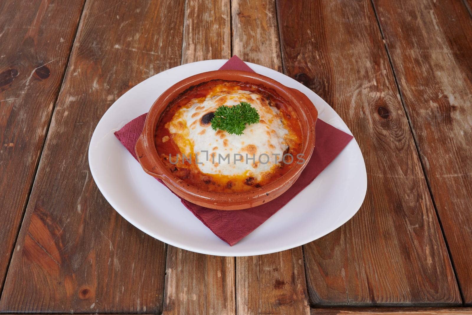 A bowl of food with a red napkin on top. The food is a type of pasta dish with cheese and herbs