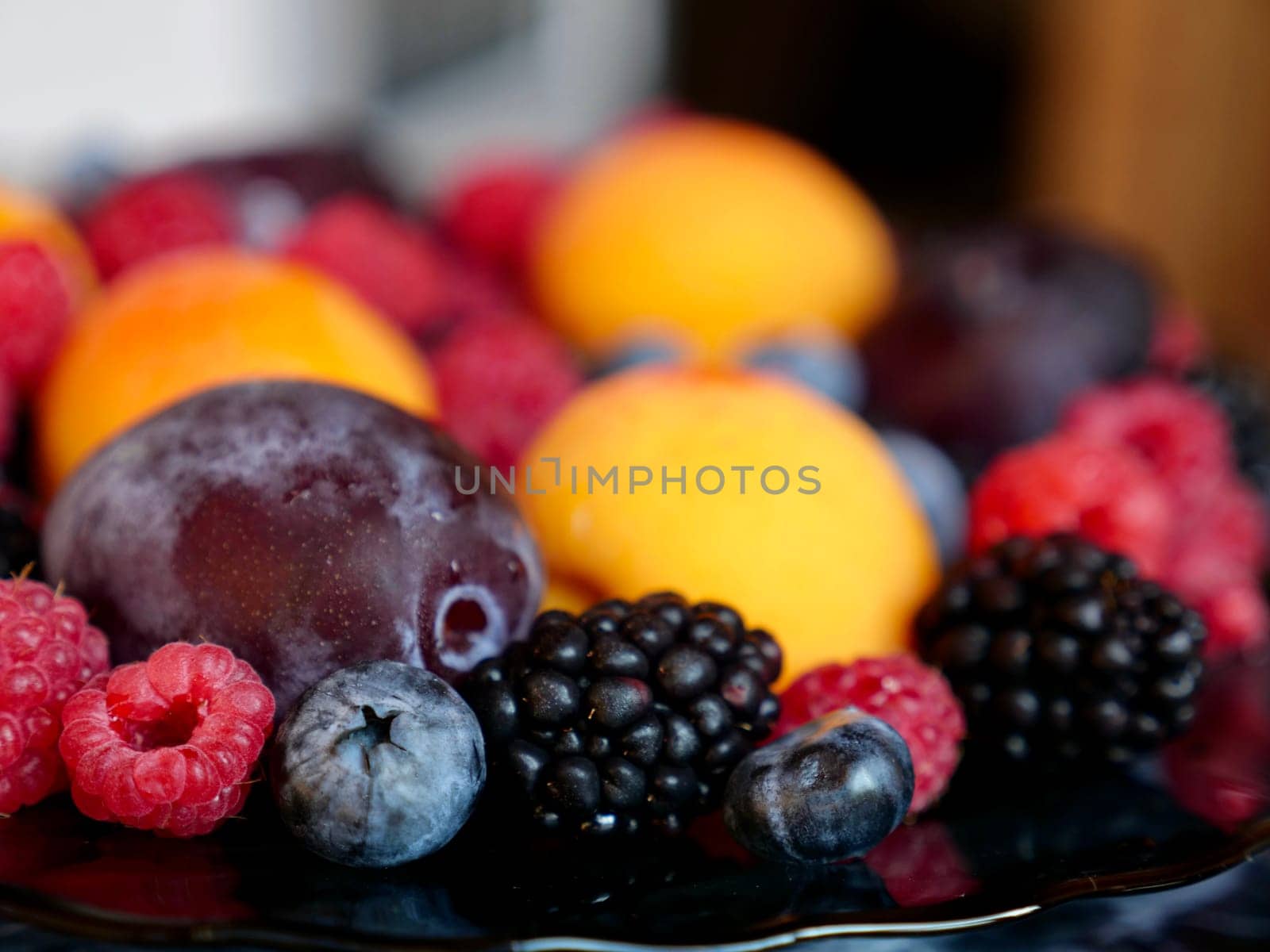 Colored background of seasonal summer fruits apricot, plum, raspberry, blueberry, blackberry in garden, close up