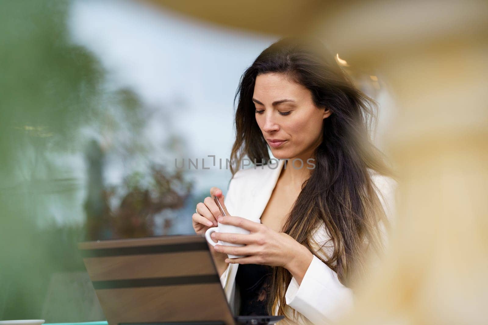 A serene moment of a woman sipping coffee while working on her laptop in a stylish caf, embodying productivity and relaxation