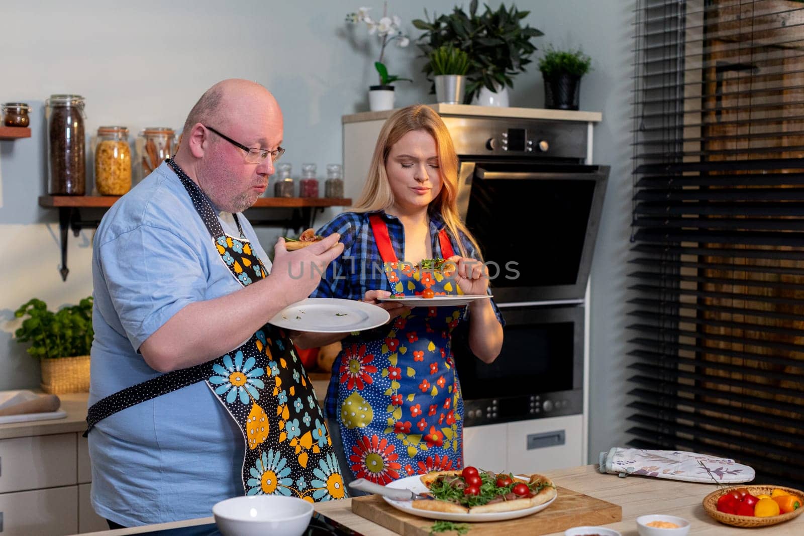 Two enthusiastic individuals are sharing a delightful and enjoyable cooking experience in a vibrant, modern kitchen