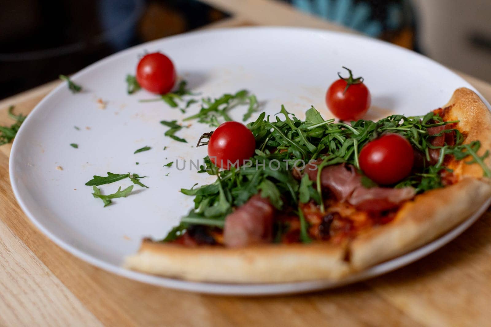 A delicious and tasty pizza slice generously topped with fresh cherry tomatoes and vibrant greens is ready to enjoy