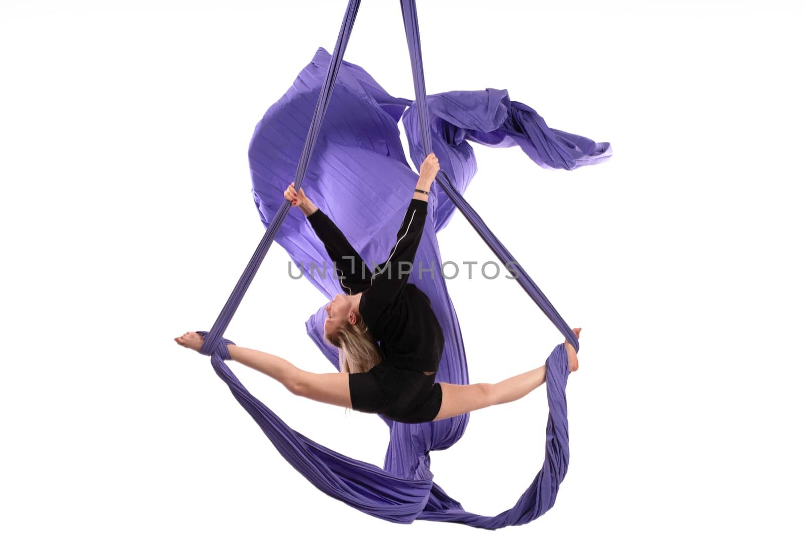 Full body side view of flexible girl performing splits on hanging aerial silk isolated white background
