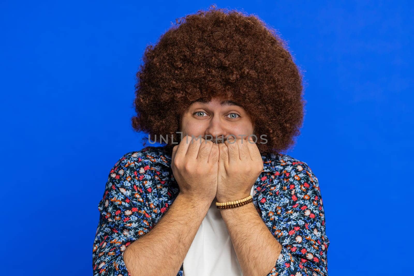 Stressed depressed man with Afro hairstyle wig terrified about danger problems suffering phobia, anxiety disorder expresses fear waving no insecure stress panic. Scared fearful guy on blue background