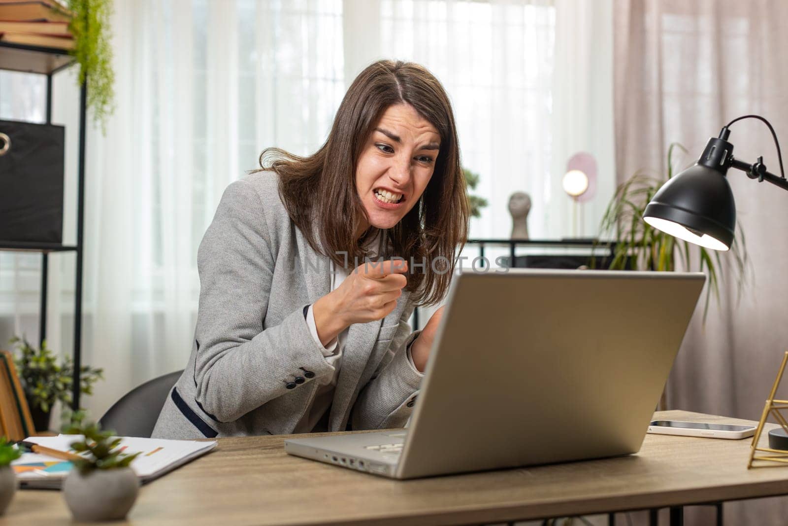 Nervous Caucasian manager quarrelling laptop call online at home office desk. Emotional businesswoman talking aggressively computer video call. Stressed lady scolding subordinates and closing laptop.