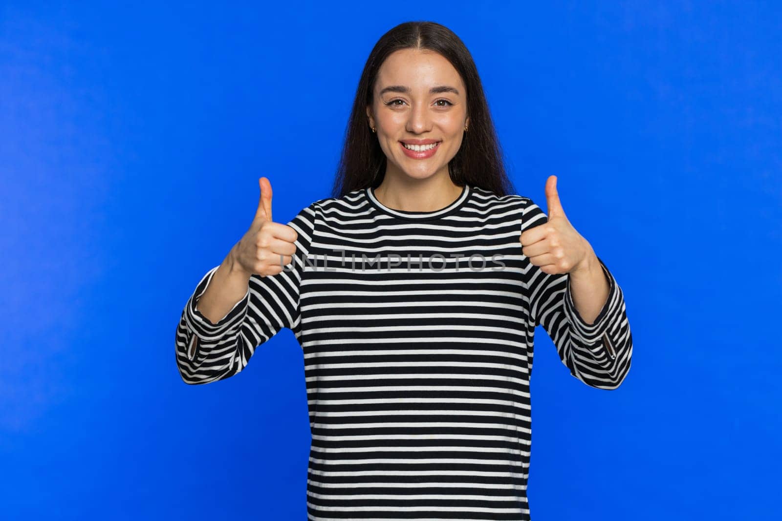 Like. Caucasian woman raises thumbs up agrees with something or gives positive reply recommends advertisement likes good idea feedback celebrating success victory. Girl isolated on blue background