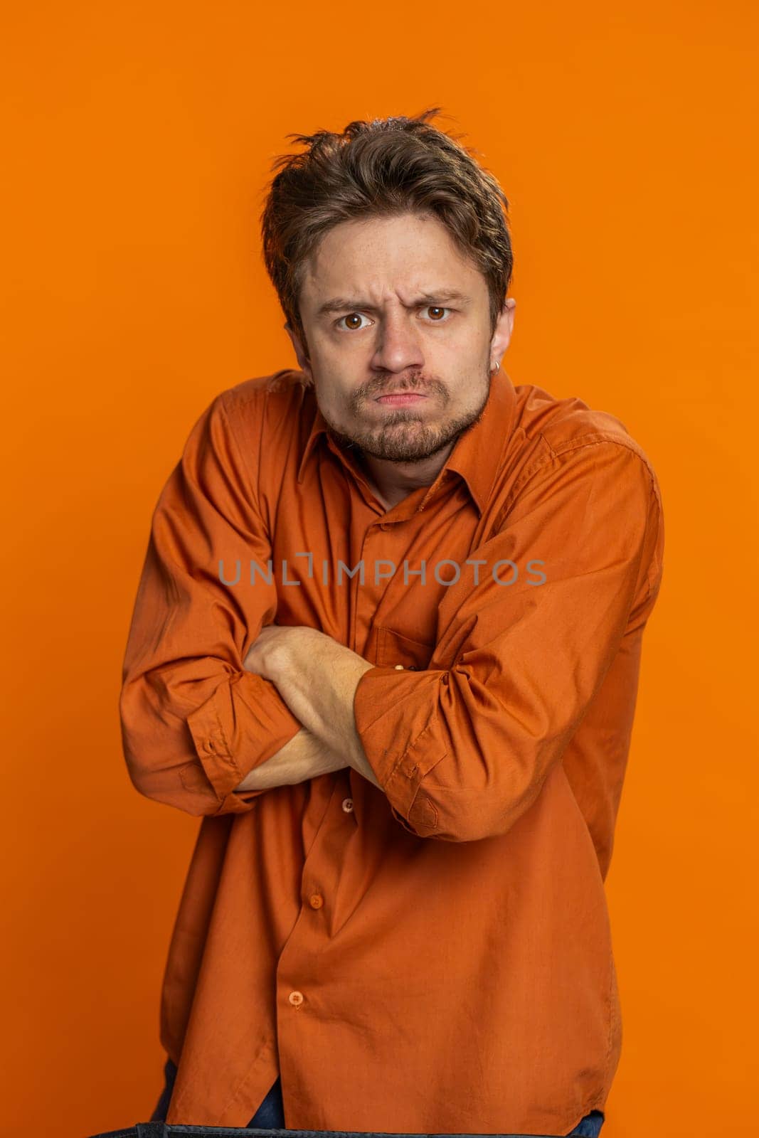 Upset frustrated annoyed man raising hands in indignant expression, quarreling asking reason of conflict problem, why such stubborn. Irritated young guy isolated on orange background indoors. Vertical