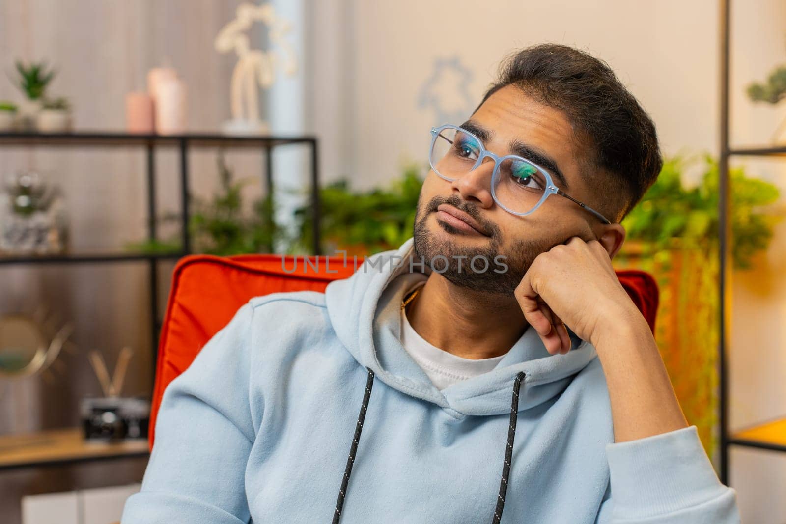Portrait of sad Indian Hindu man guy sits at home looks pensive thinks over life concerns or unrequited love, suffers from unfair situation. Problem, break up, depressed feeling bad annoyed, burnout