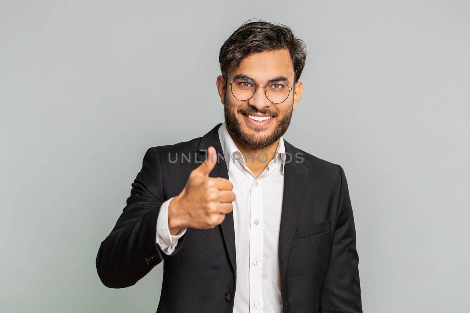 Like. Indian businessman raises thumbs up agrees with something or gives positive reply recommends advertisement likes good idea feedback, celebrating success victory. Man isolated on gray background