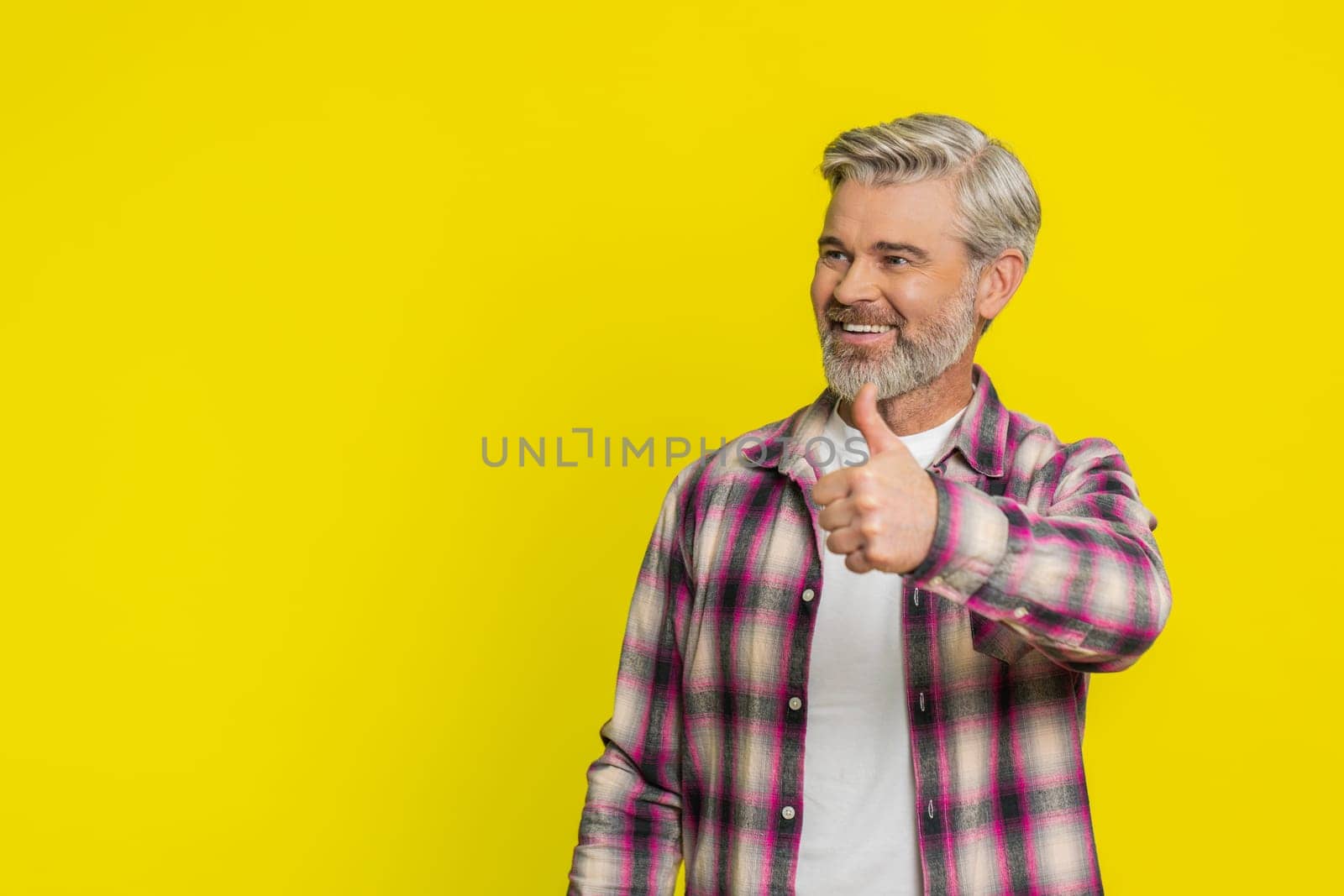 Like. Caucasian man raises thumbs up agrees with something or gives positive reply recommends advertisement likes good idea feedback celebrating success victory. Guy isolated on yellow background