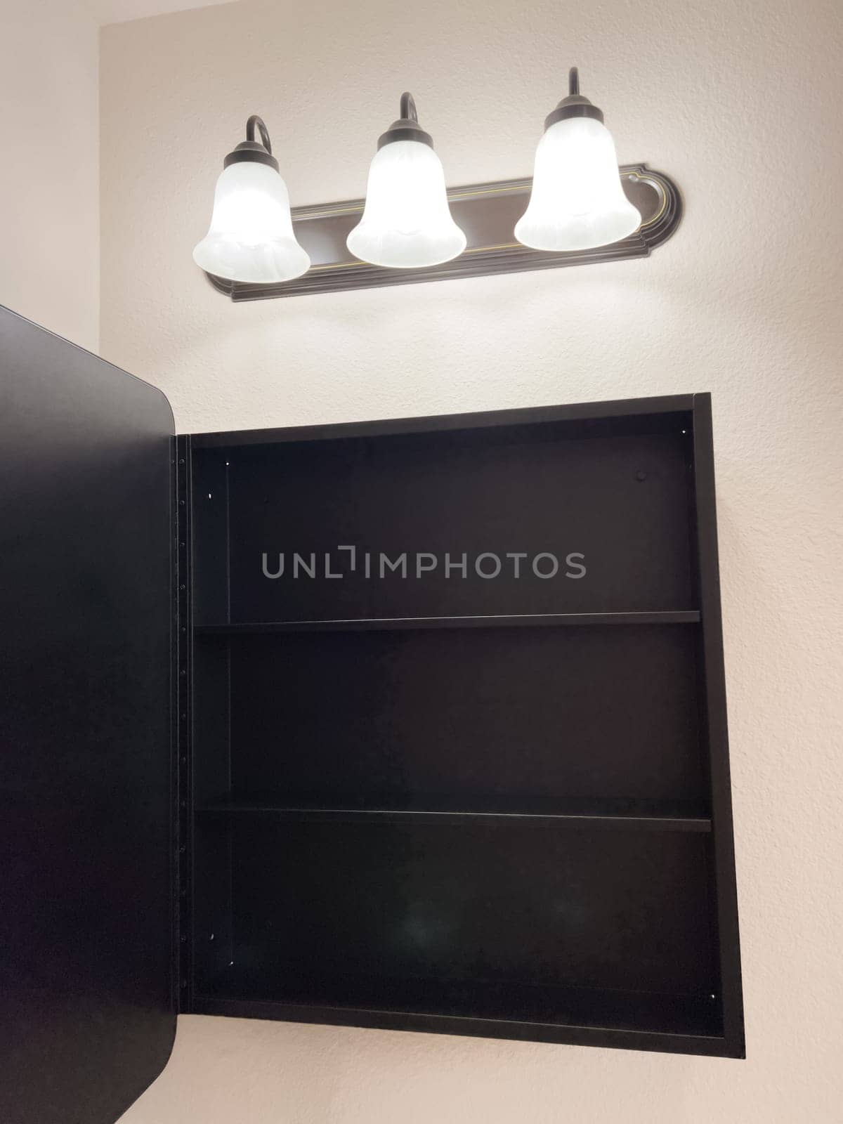Broomfield, Colorado, USA-January 25, 2025-A stylish bathroom vanity featuring a large rectangular mirror with a black frame, a white sink with a black faucet, and a beige countertop. The vanity is complemented by a three-light fixture above the mirror, providing ample lighting. A black towel bar is mounted on the wall, enhancing the modern design. The bathroom has a clean, minimalist look with neutral tones and functional elements.