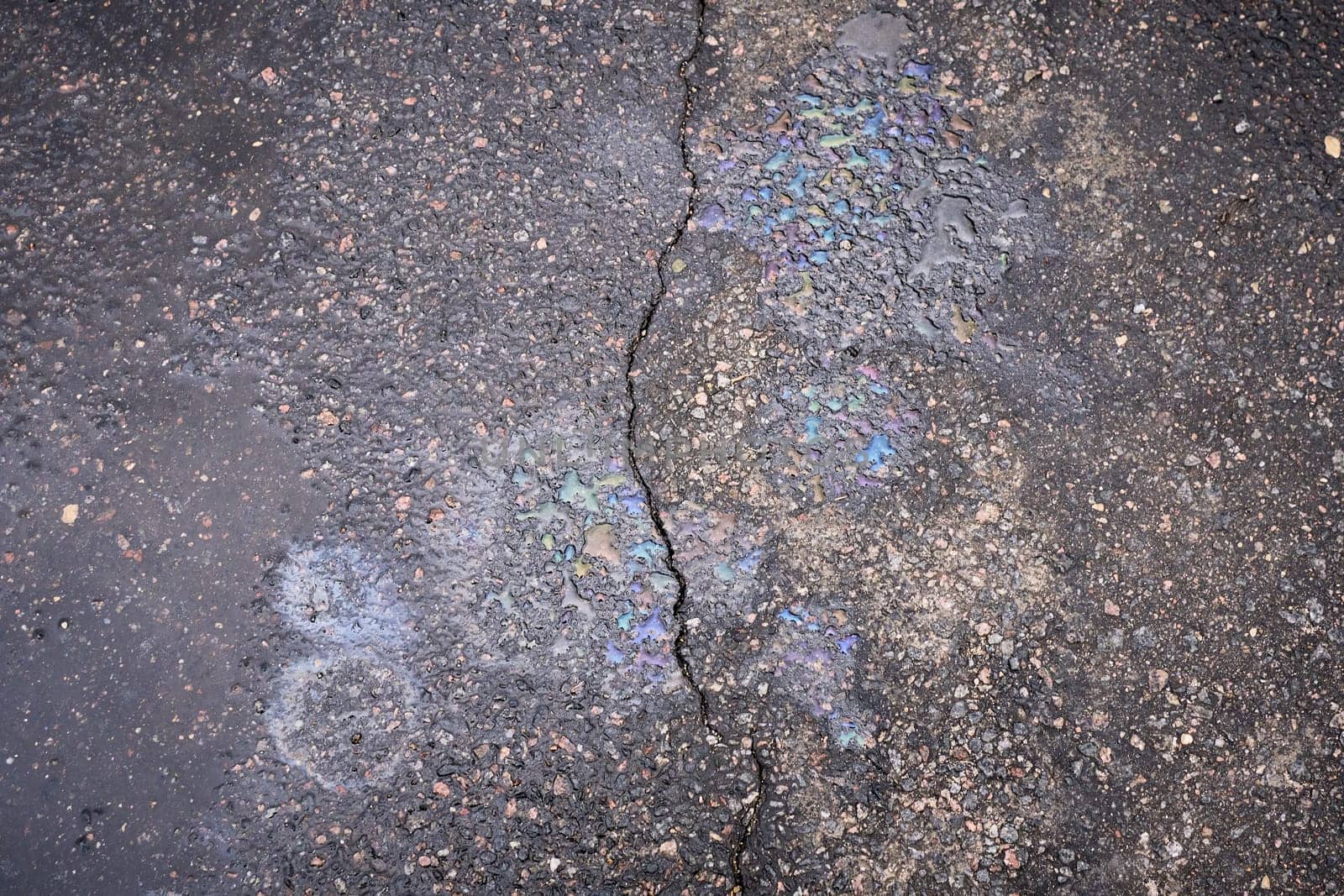 Gasoline or oil spill creating rainbow colors on asphalt road surface