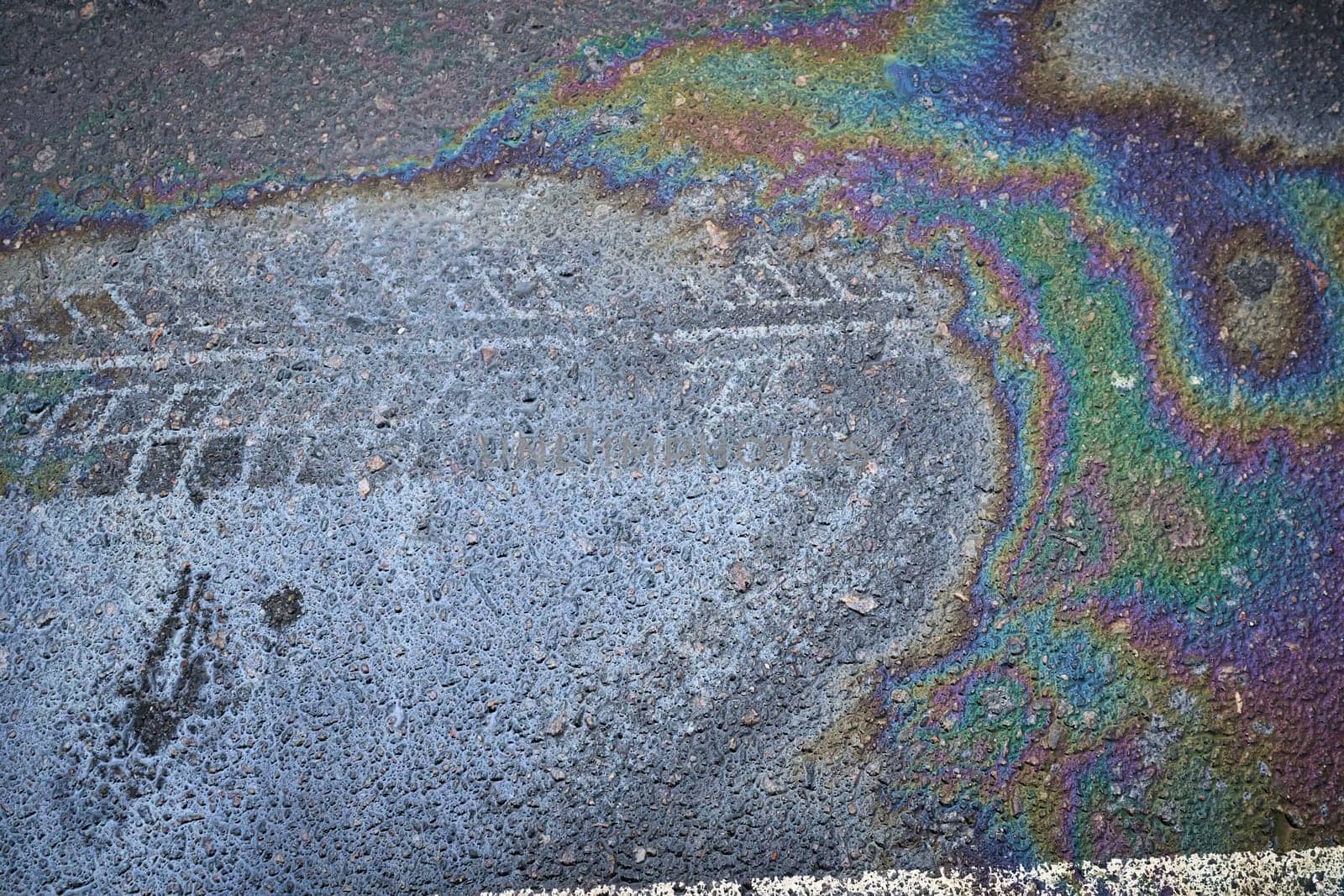 Gasoline rainbow creating colorful pollution on wet asphalt road