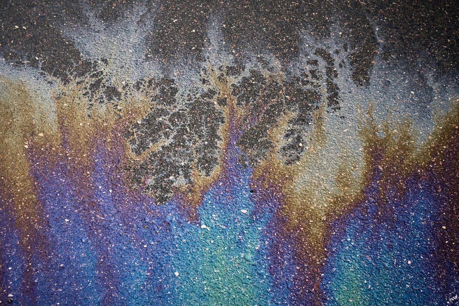 Gasoline rainbow on asphalt creates pollution awareness design