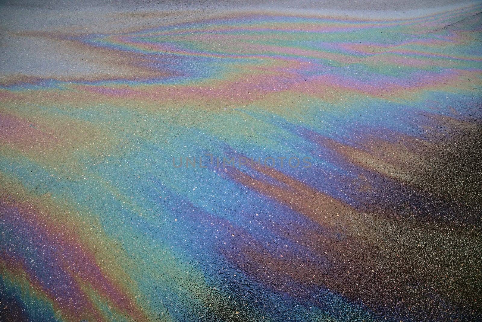 Gasoline rainbow creating colorful patterns on asphalt road