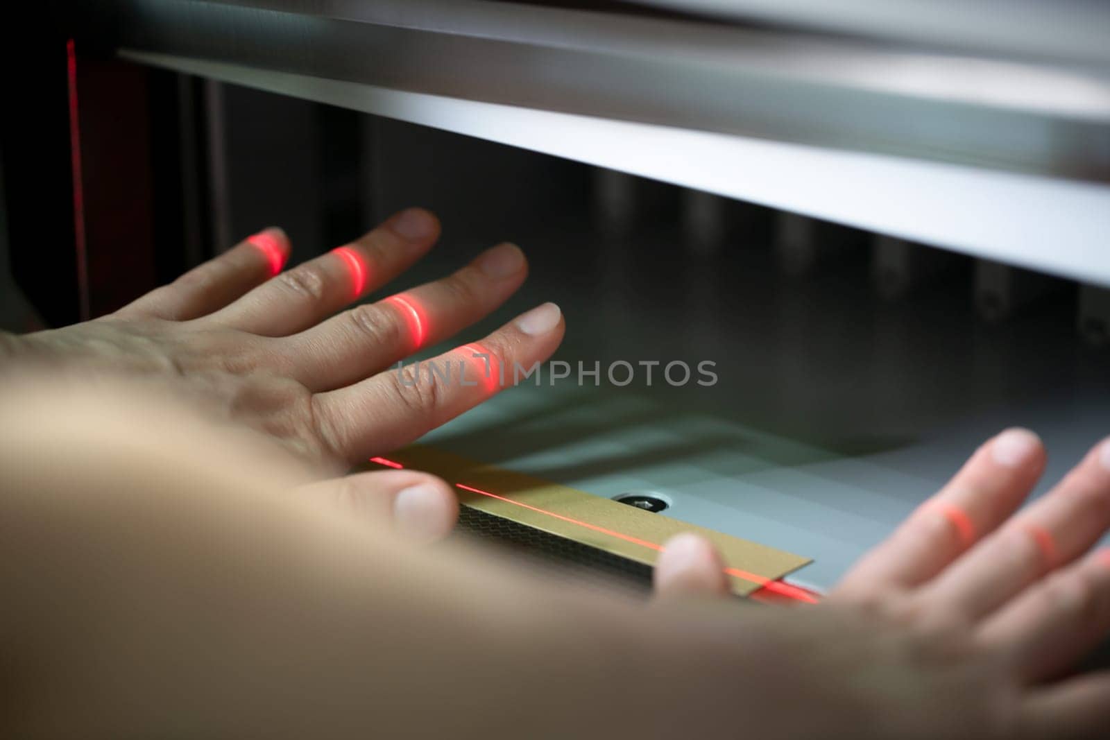 Crop unrecognizable female employee checking and setting up modern digital paper cutting machine in workshop
