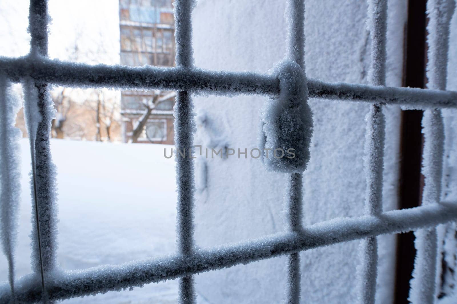 Metal wire door door handle and keyhole are covered with frost - icy lock covered with snowflakes - concept of cold winter