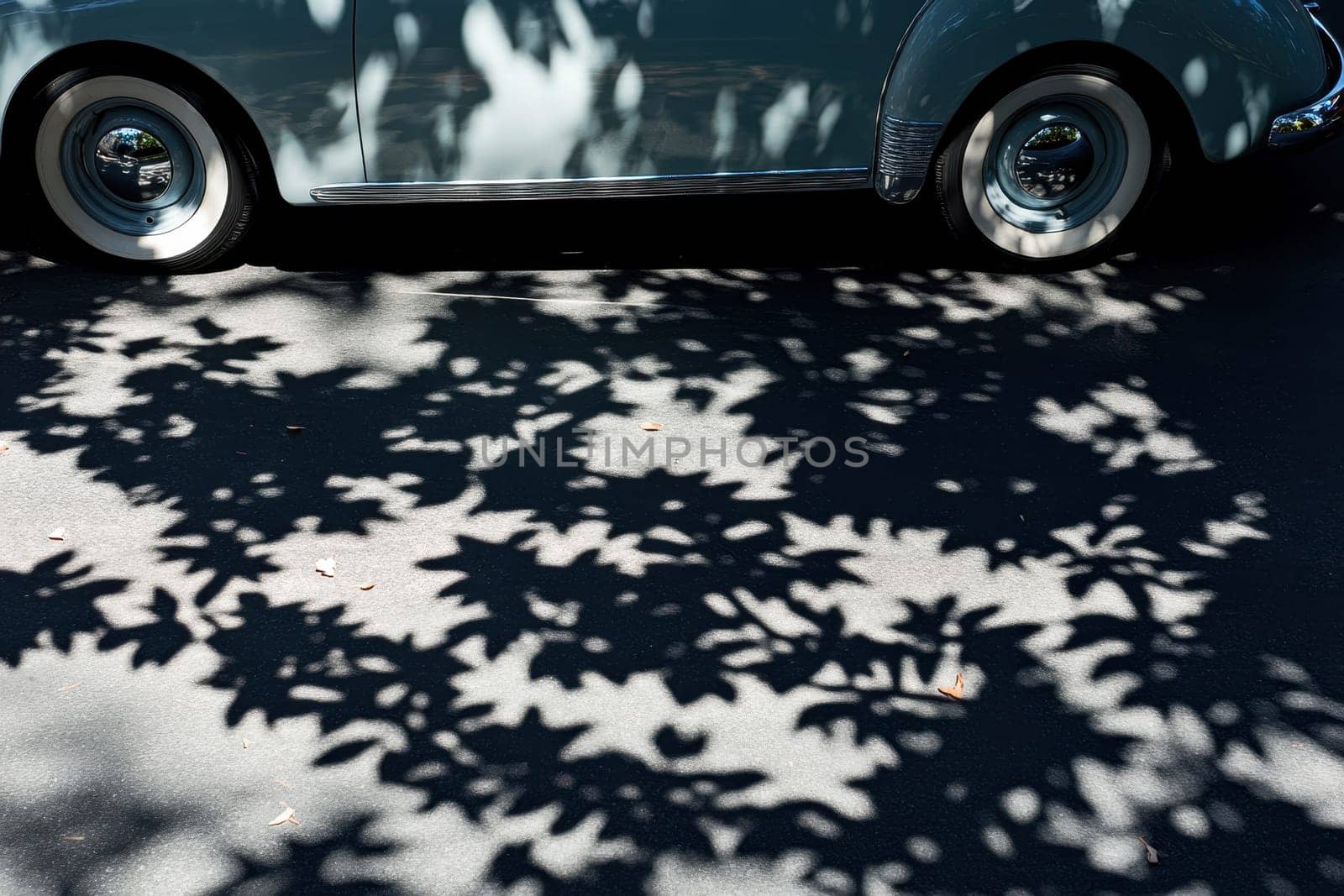 A car is parked on the side of the road, and its shadow is cast on the pavement. The car is a vintage model, and the shadow it casts is a beautiful, intricate design. The scene is peaceful and serene