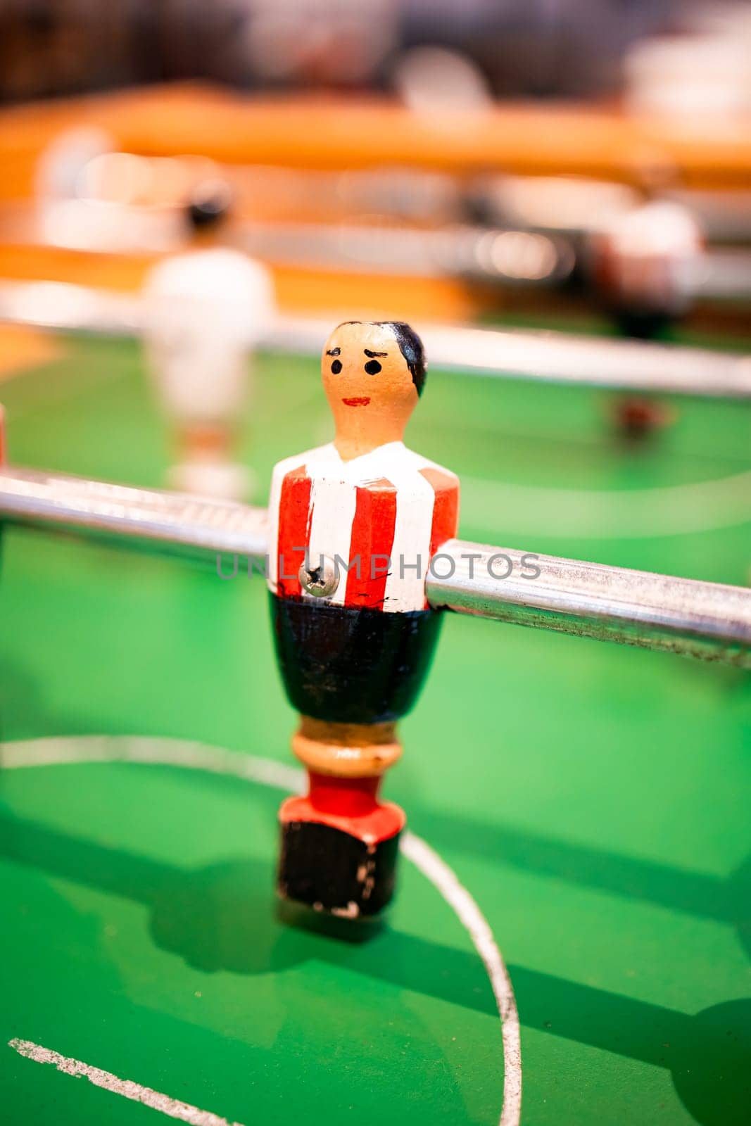 Close up of vintage table football player figurine on green foosball field.