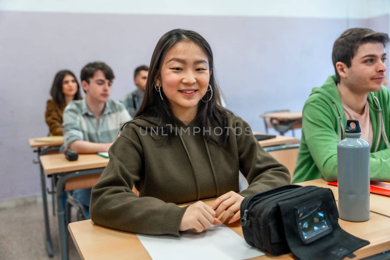 Young asian student smiling while engaging in a lesson with classmates in a vibrant university classroom, highlighting the joy of learning