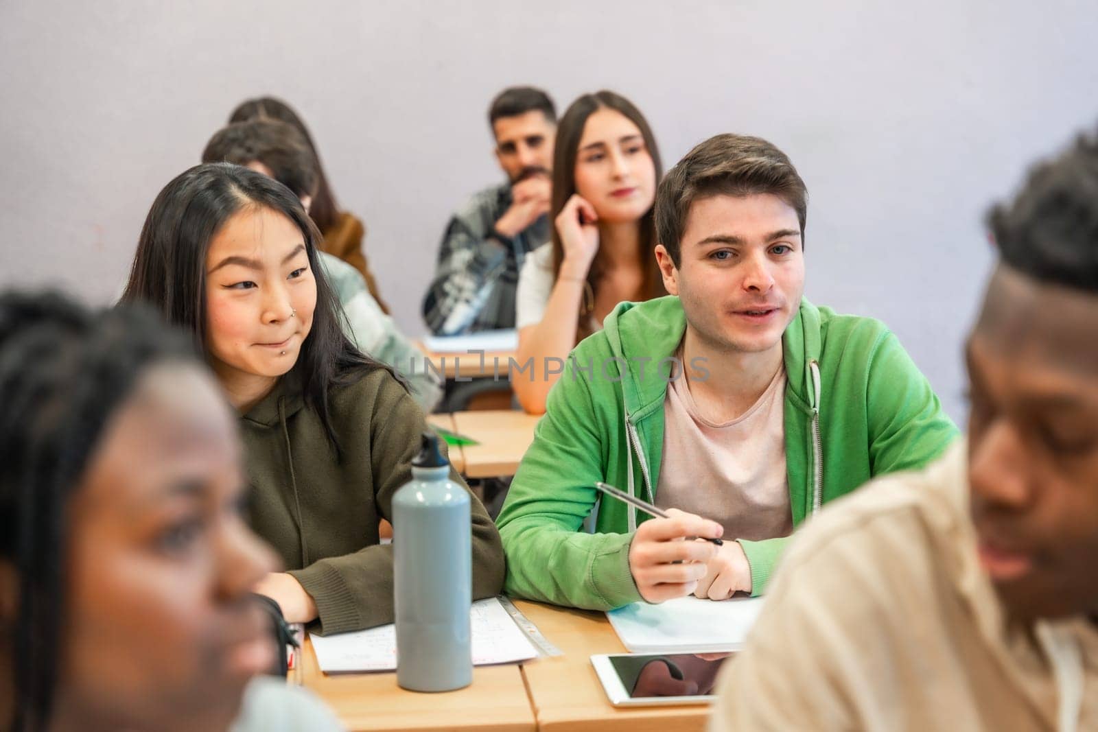 Multi ethnic university students listening to the teacher and following a lesson in the classroom