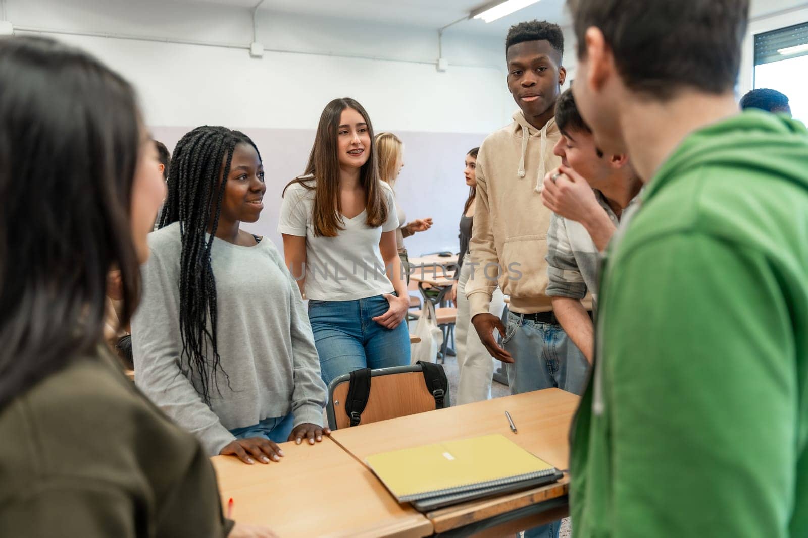 Diverse group of university students engaged in teamwork, discussing and sharing ideas around a desk in a classroom setting