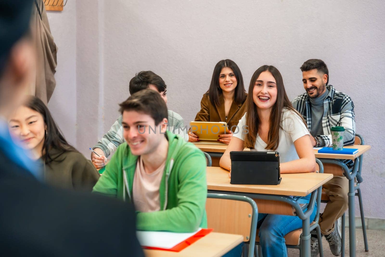 Multi ethnic university students attending a lecture and using digital tablets, enjoying learning and academic pursuits