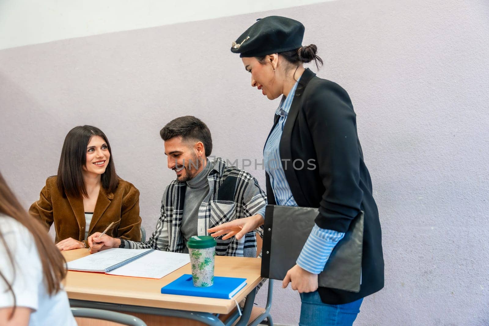 University students collaborating on a project, receiving guidance from their professor in a classroom setting