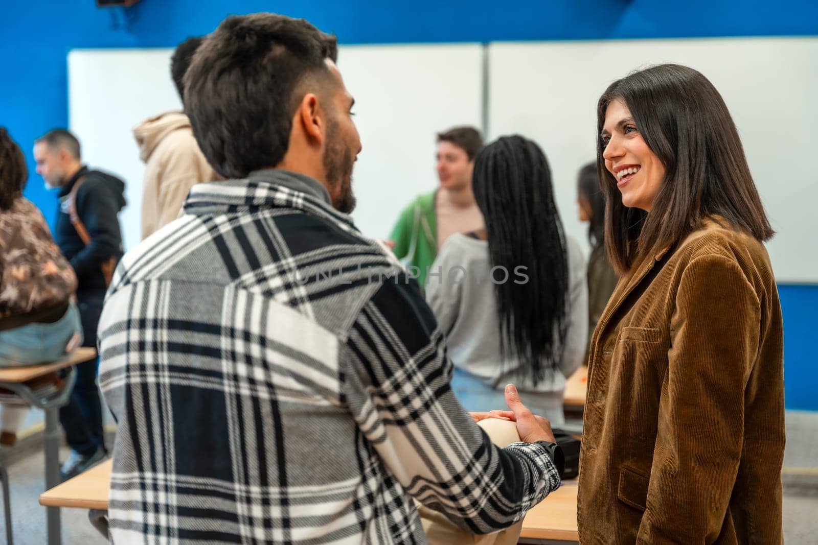 Multi ethnic university students chatting with their teacher after class, discussing lesson topics and asking questions