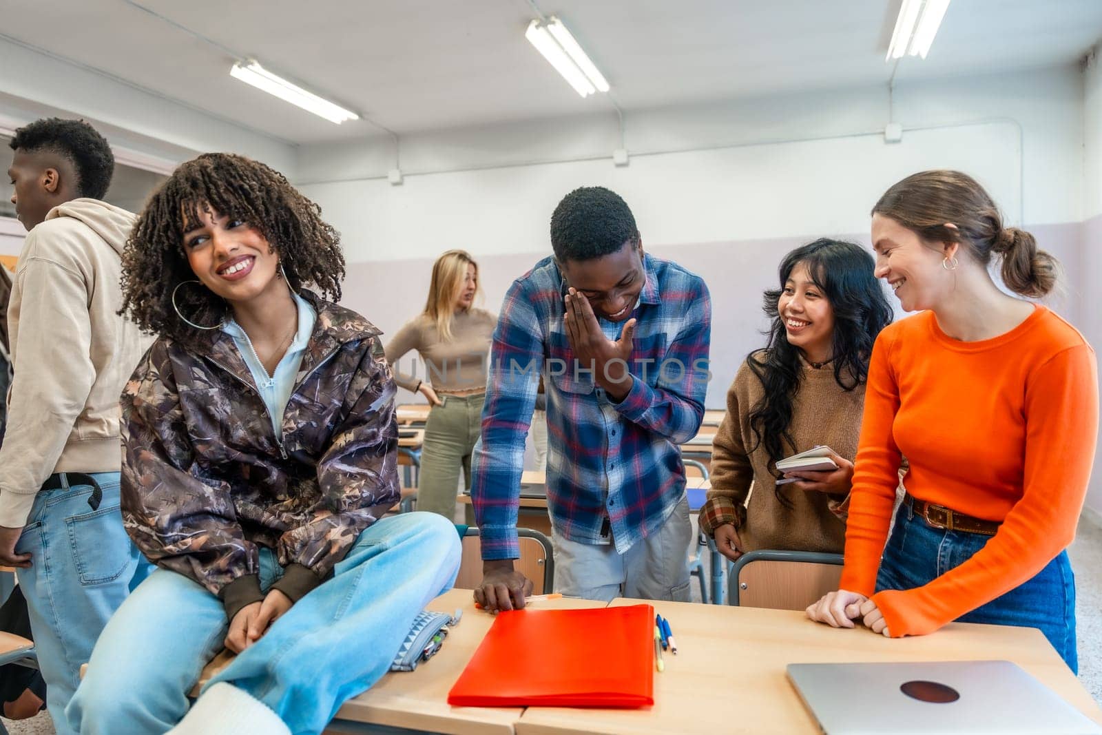 Cheerful multi ethnic university students enjoying time together, laughing and studying in a classroom