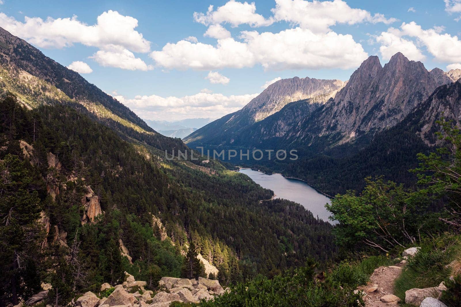 panoramic view of a mountain range with a lake in the valley, the sky is clear and the sun is shining brightly