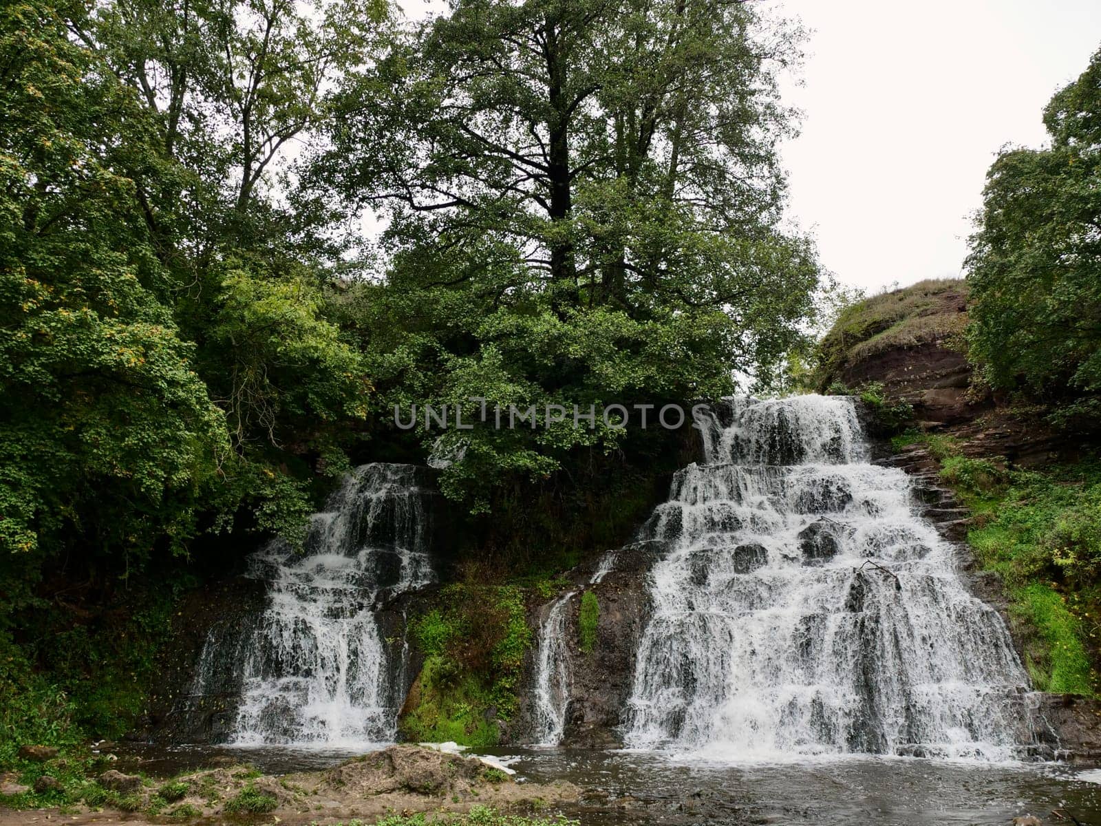 Chervonohorod Dzhuryn waterfall in summer in Ukraine. Travel nature Carpathian Mountains in cloudy cool weather,