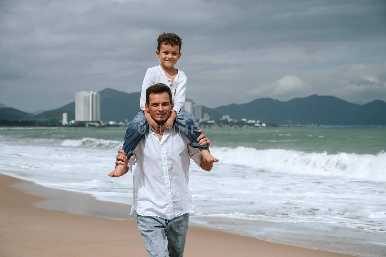 happy father with child son on the beach by the sea in summer on vacation