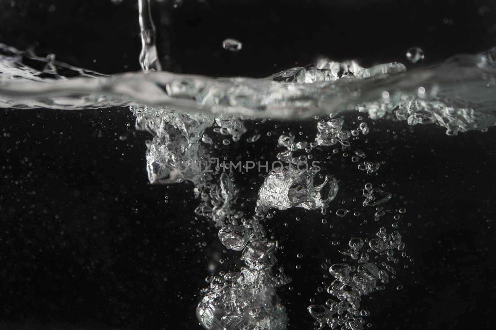 Water splashing as it's poured into aquarium tank, black background