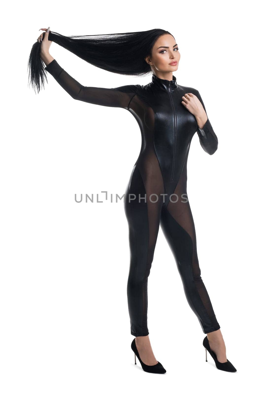 Seductive brunette female in black leather bodysuit take away long hair and looking at camera on white isolated background