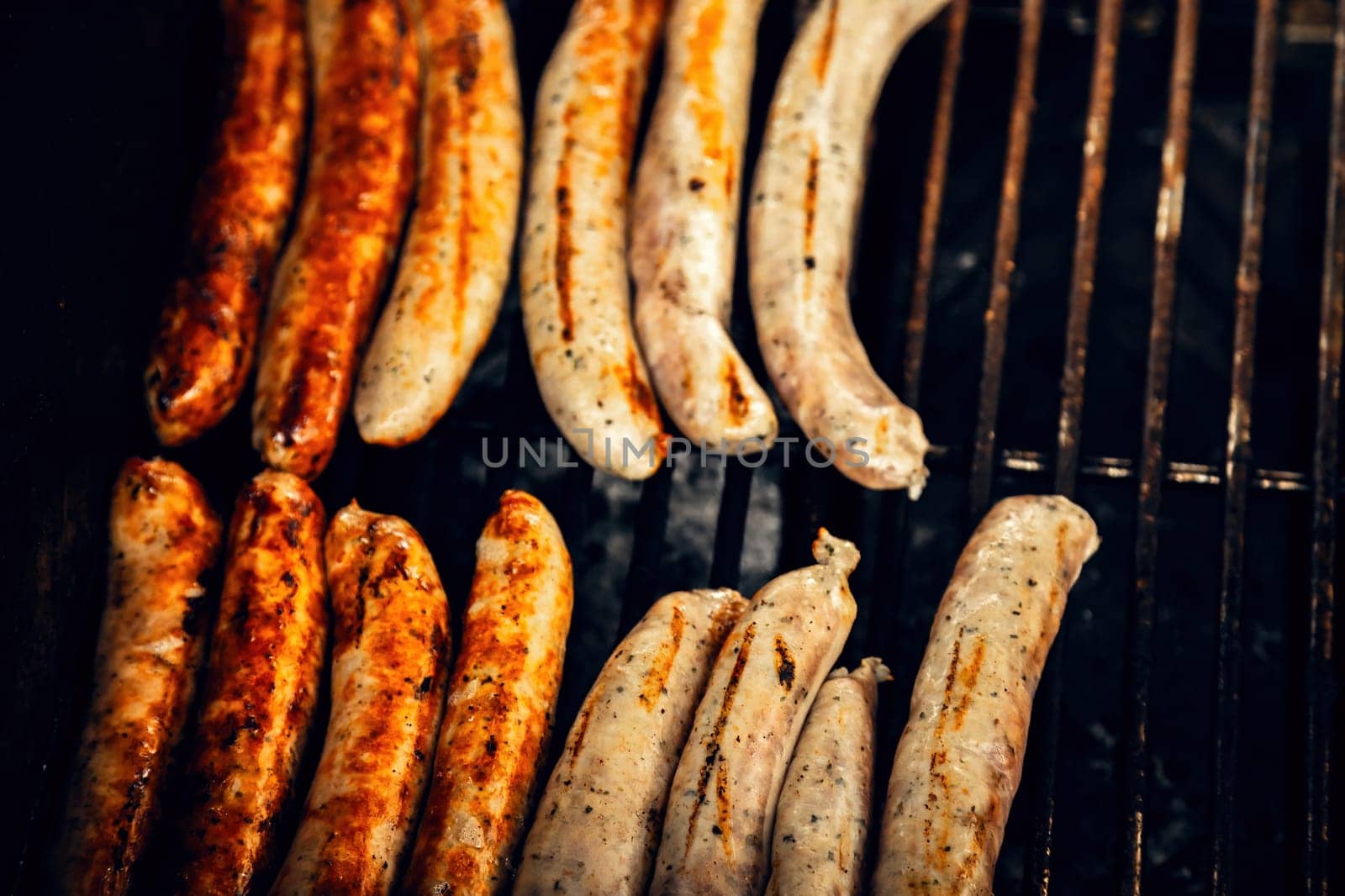 Grilled sausages sizzling on a barbecue, showing a mix of golden brown and charred textures. A perfect shot capturing the essence of barbecue, summer gatherings, and culinary delights