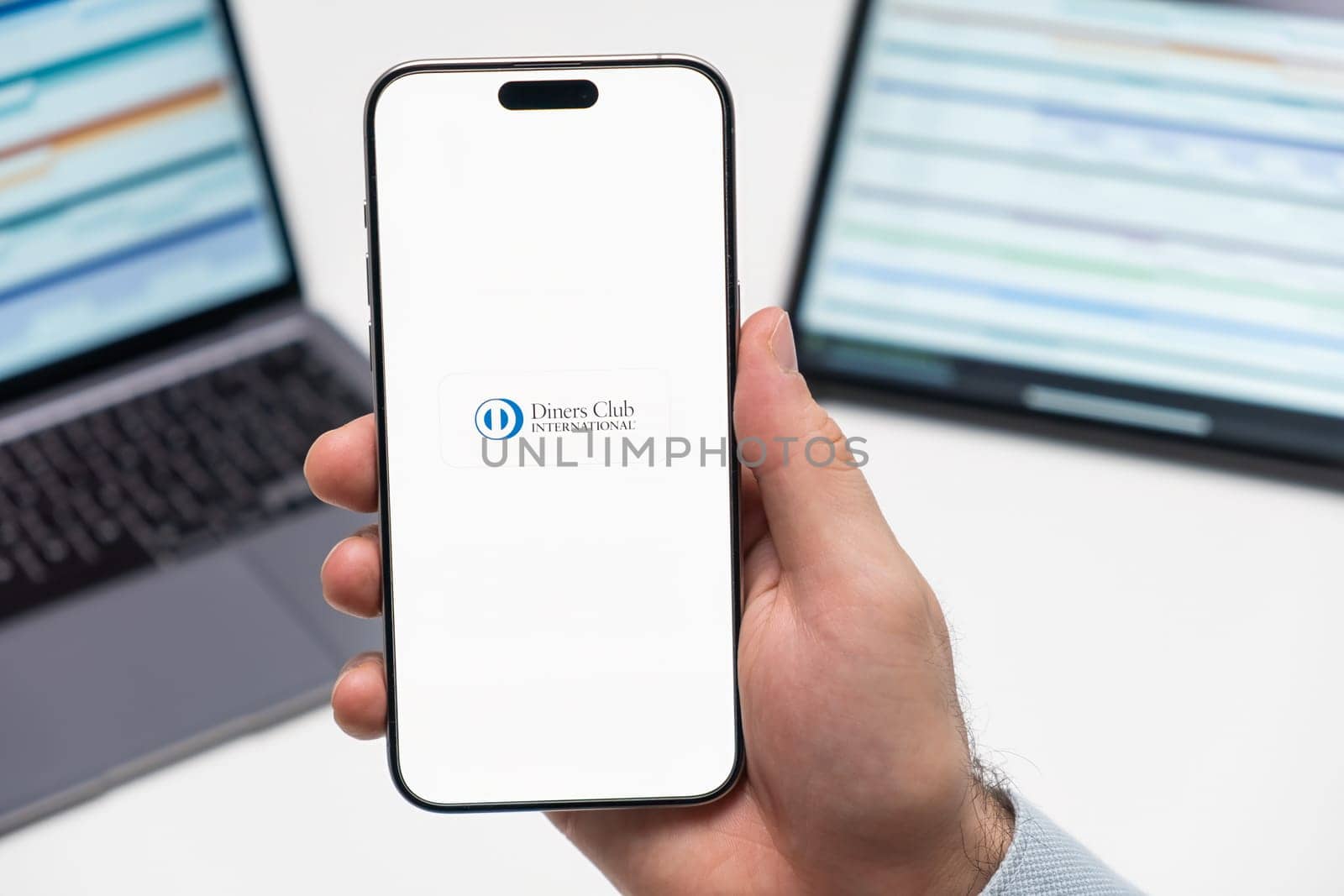 PRAGUE, CZECH REPUBLIC - JANUARY 21 2024: Diners Club International logo on the screen of smartphone in mans hand on the workplace background.