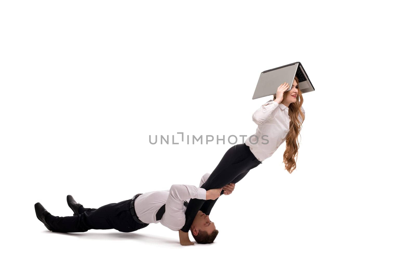 Cooperation concept studio shot of businessman supporting legs of female coworker using laptop on white background