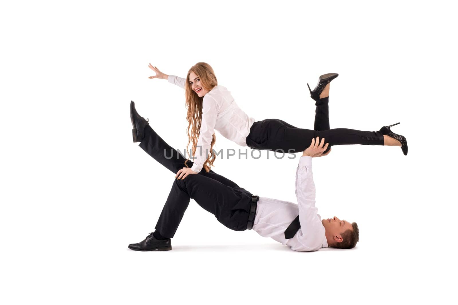 Side view of male manager in formal wear lifting cheerful female colleague against white background