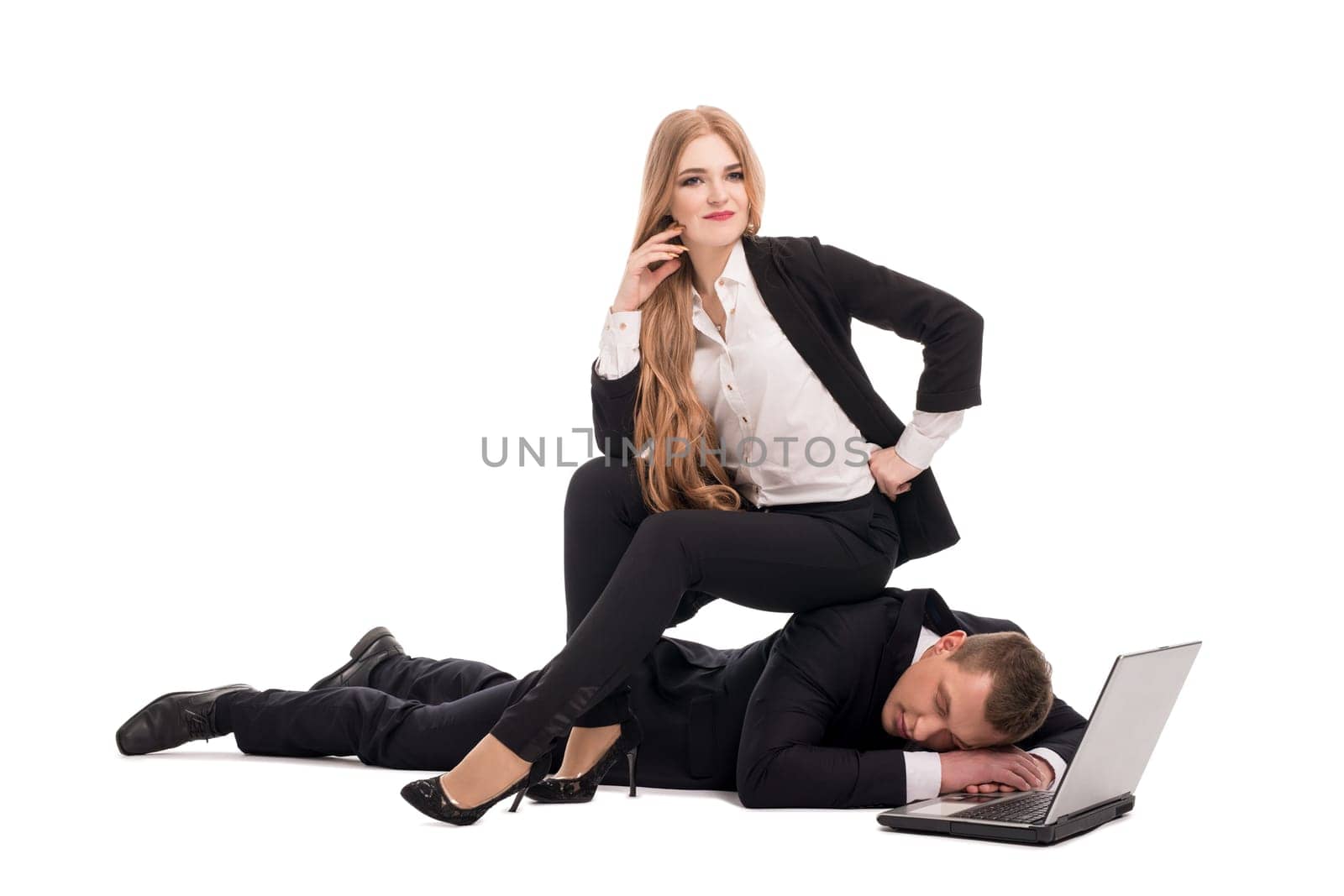 Female entrepreneur in suit sitting on back of exhausted businessman near modern netbook against white background
