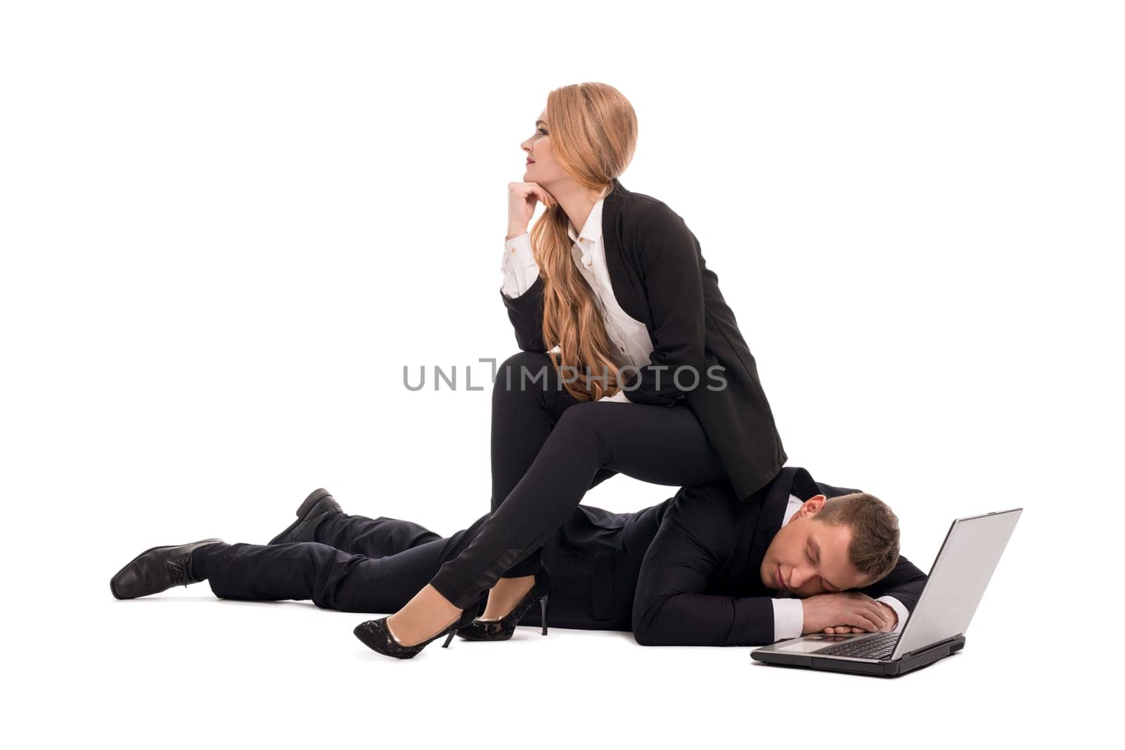 Full length of dreamy young businesswoman sitting on back of tired man sleeping near open laptop representing business and relationship concept isolated on white background