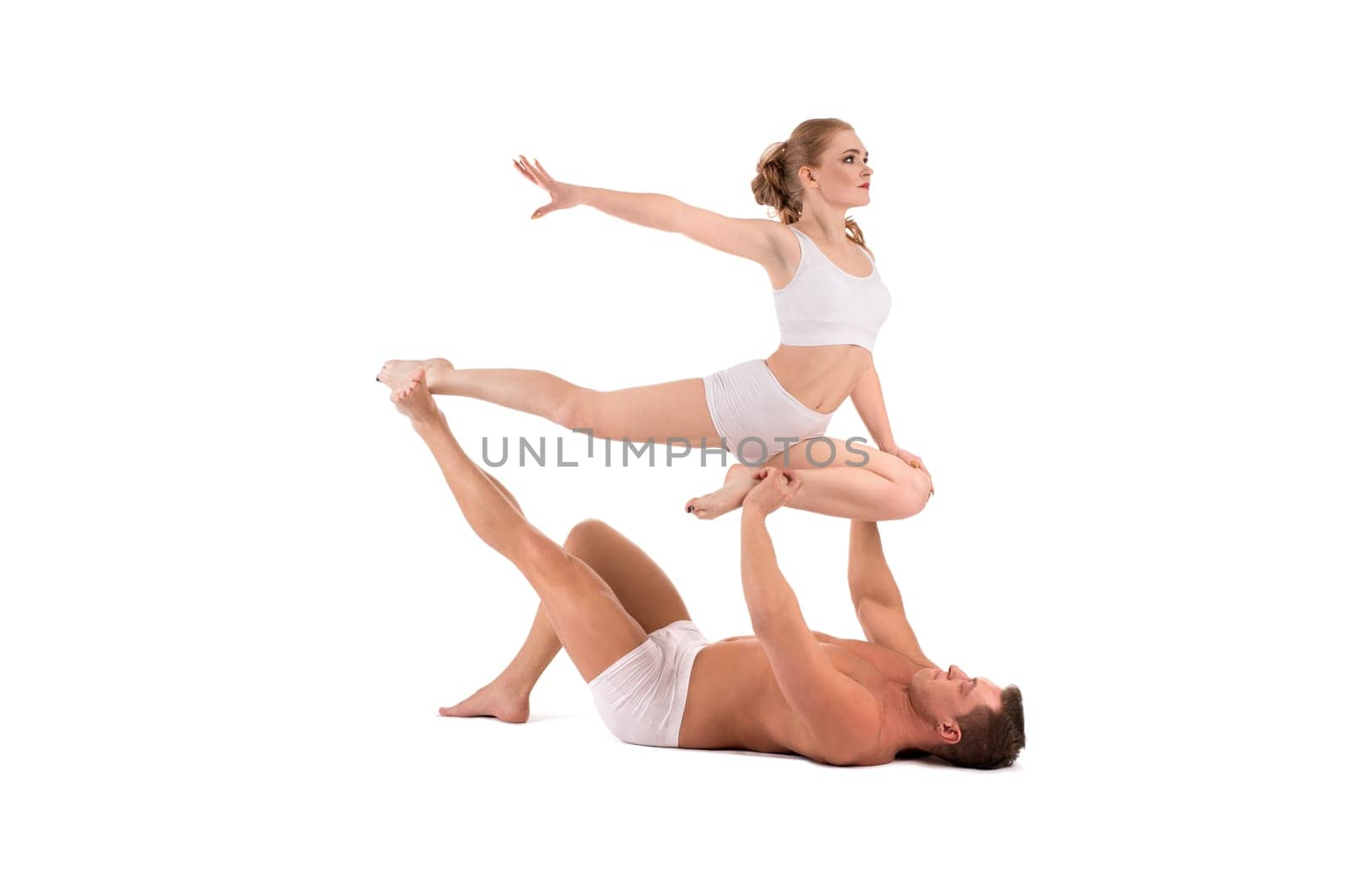 Full body side view of strong shirtless muscular man supporting female partner performing graceful acrobatic movement isolated on white background