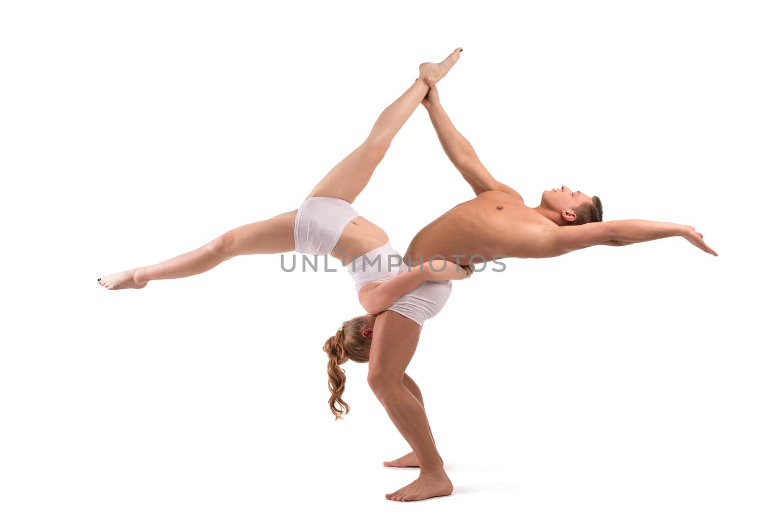 Full body side view of flexible young man and woman in white underwear doing acro yoga against white background
