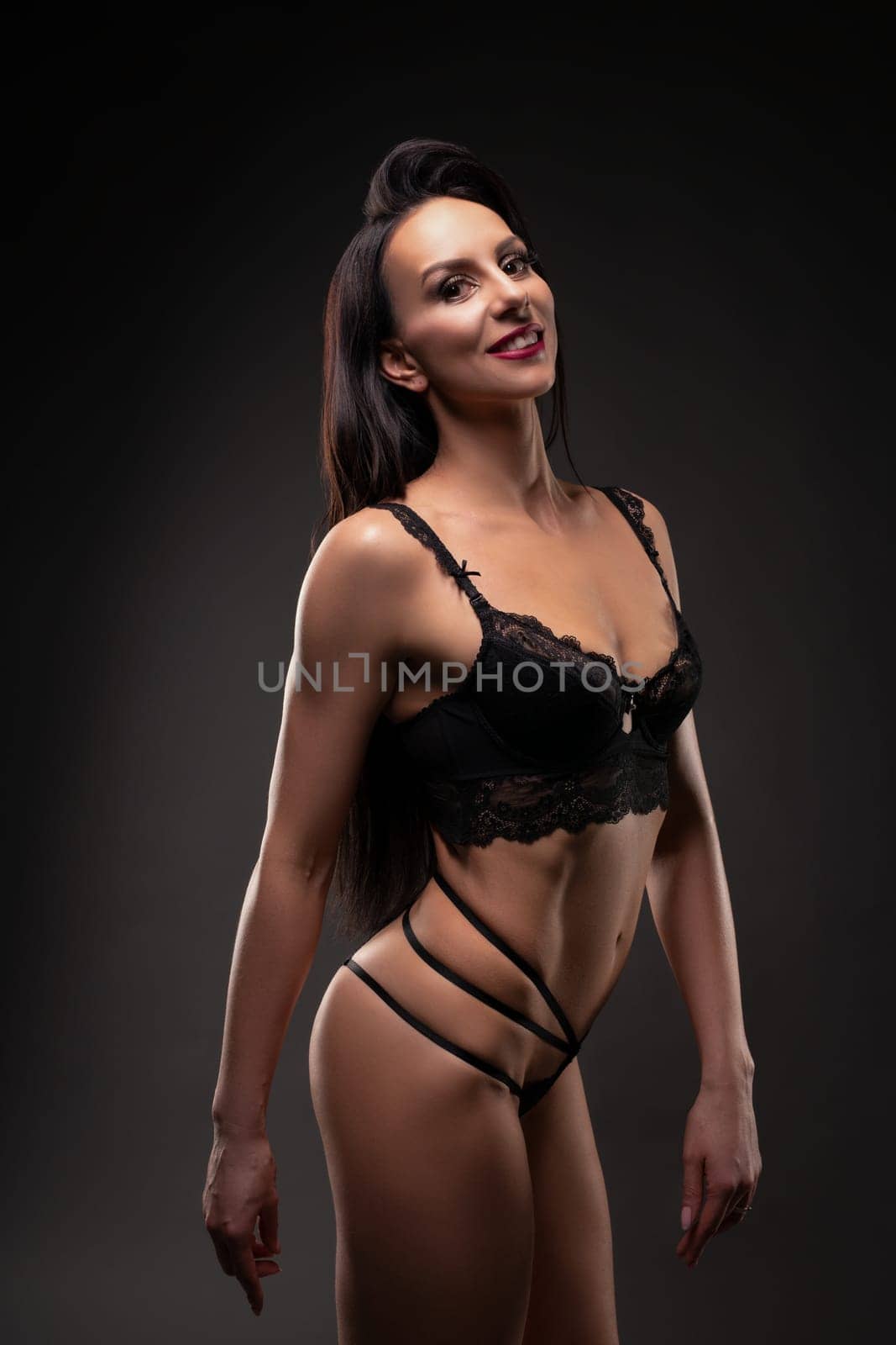 Strong brunette in black lingeries ready for fitness competition looking at camera